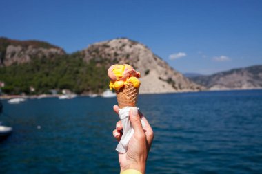 Dondurma külahı sıcak yaz gökyüzüne kadar uzanıyor. Dondurma külahını tutan kadın. Vanilyalı dondurma.