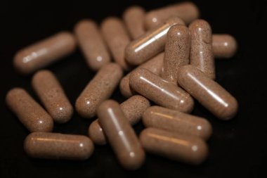Kahverengi vitamin tozu dolu şeffaf kapsüller. Arka planda yüksek kalite büyük baskı.