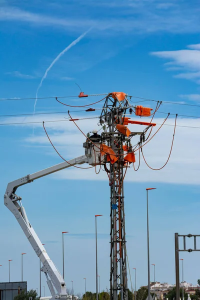 A unrecognizable worker in a hydraulic lift basket doing maintenance work on a power line. Vertical. Copy space