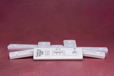 Pile of coronavirus antigen tests, with positive and negative results, on red background