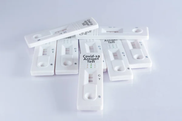 Pile of coronavirus antigen tests, with positive and negative results, on white background