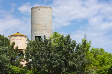Old small water tank in ruins, unused for being obsolete for the city, next to another modern and large one