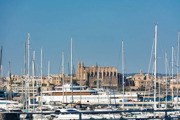 Palma de Mallorca, Balearic islands, Spain. July 17, 2022 - View of the Cathedral and the Royal Palace of the Almudaina, with the masts and ships of the marina