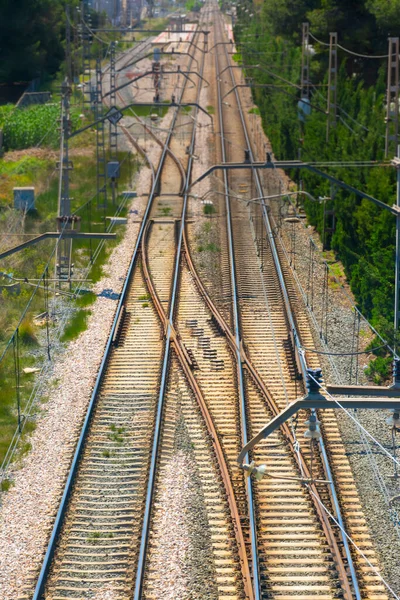 Straight train tracks with rail change, with a platform in the background, with selective blur