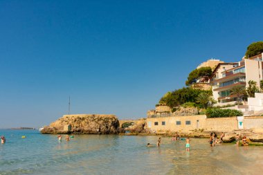 Palma, Mallorca, İspanya. 17 Temmuz 2022 - Cala Major plajında Es Pujolar, kıyıya yakın küçük bir adaya küçük bir köprü. Arka planda ses Illetes kulesi
