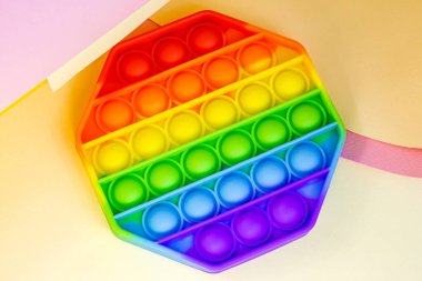 Moda olan basit gamzelerin üst görüntüsü ya da parlak kağıt arka plandaki çocuklar için duyusal bir oyuncak. Popüler anti-stres silikon çocuklar gökkuşağı renklerinde kabarcıklar oluşturur.