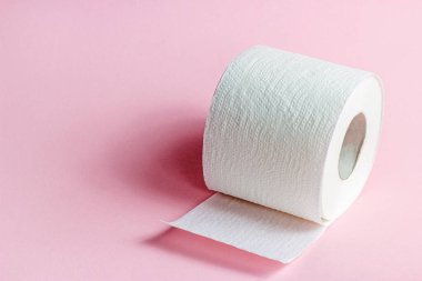 Açık pembe zemin üzerinde beyaz tuvalet kağıdı rulo kopyalama alanı ile.