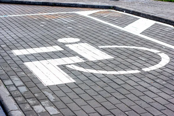 Parking lot for people with disabilities white road sign painted on asphalt in garage.