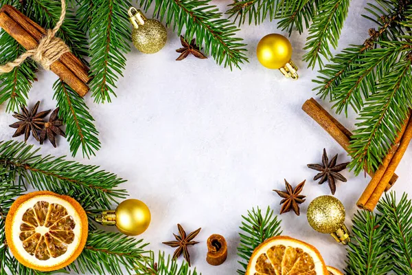 Noel ağacının yeşil köknar dalları, altın takılar, portakallar ve baharatlar Noel çelenkleri çerçevesi olarak beyaz arka planda tebrik kartları için. Kopya alanı ile geleneksel kış tatili şablonu.