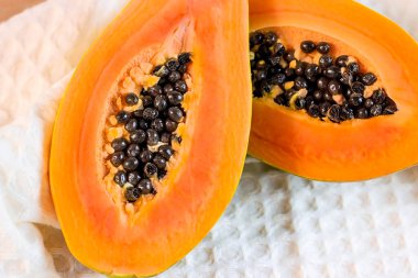 Açık arkaplanda siyah çekirdekli parlak turuncu egzotik papaya meyveleri..