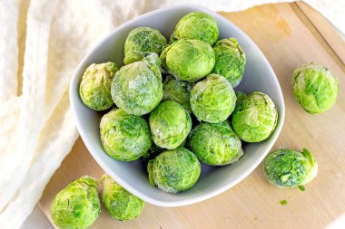 Pek çok donmuş Brüksel lahanasının üst görüntüsü beyaz kasede filizlenir..