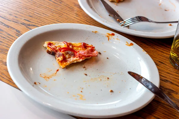 Dirty messy plates after pizza eating with unclean used utensils in the cafe.