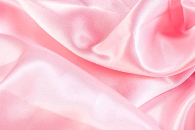 Yumuşak desenli arka plan olarak açık renkli pembe renkli ipek dalgalı tekstil deseni. Gül renkli yumuşak saten kumaş örtüsü.