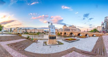ÜSKÜP, NORTH MACEDONIA, 01.08.2020: Günbatımında Üsküp Şehir Merkezi - panoramik manzara. Üsküp 'ün mimarisi ve binaları. Arkeoloji Müzesi, Taş Köprü, Justinian Anıtı.