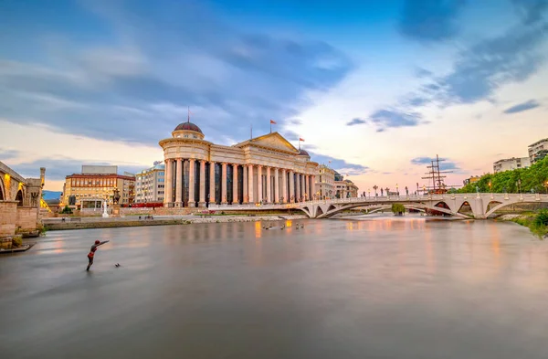 ÜSKÜP, NORTH MACEDONIA - 01.08.2020: Üsküp şehir merkezi gün batımında şehir ışıkları Vardar Nehri 'ne yansıdı. Kuzey Makedonya.