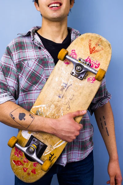 Giovane uomo che tiene il suo skateboard — Foto Stock