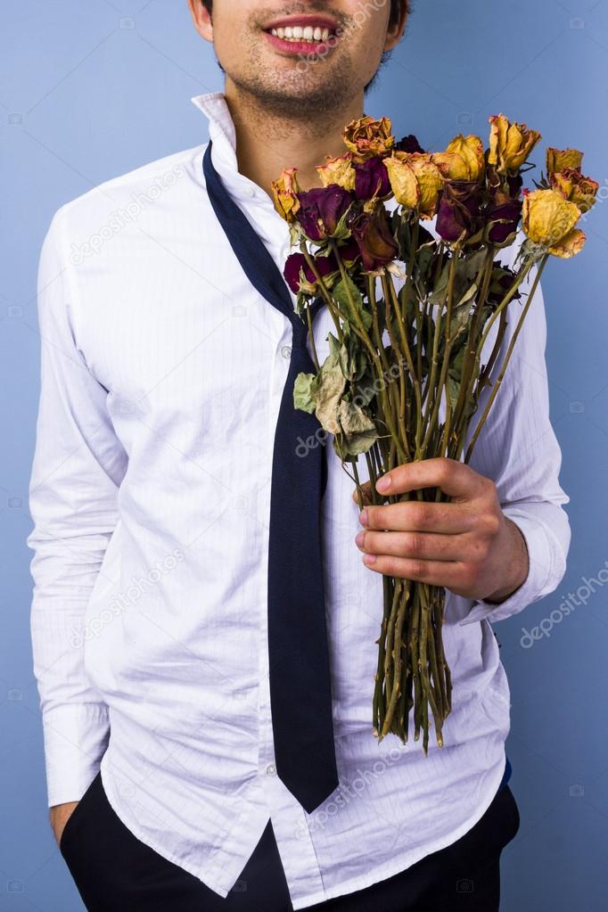 Young man with withered flowers