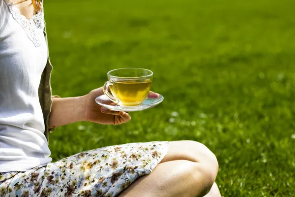 Jonge vrouw drinken thee in het park — Stockfoto