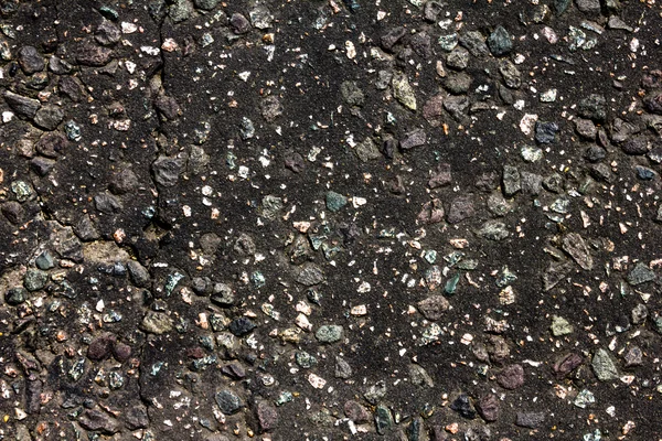 Dark rock background with pebbles and cracks — Stock Photo, Image