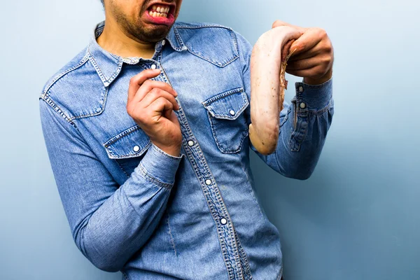 Squeamish homem segurando uma língua de boi cru — Fotografia de Stock