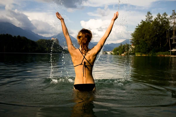 山の湖ではねかける女性 — ストック写真