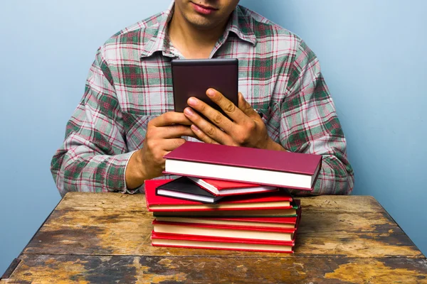 Молодой человек читает на цифровом читателе — стоковое фото