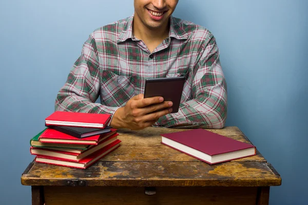 Junger Mann zieht Lesegerät Büchern vor — Stockfoto