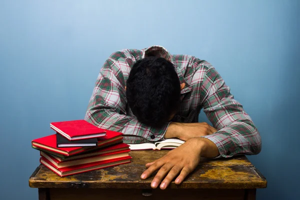 Joven durmiendo en el escritorio después de estudiar — Foto de Stock