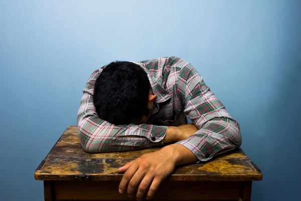 Молодой человек спит за столом — стоковое фото