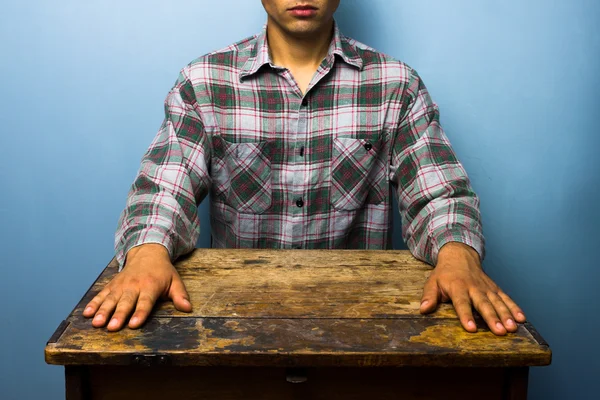 Человек, сидящий за столом в напряженной позе — стоковое фото