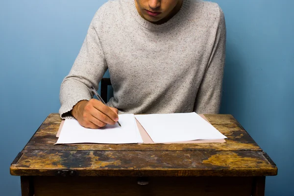 Young man writing at desk — Stock Photo, Image