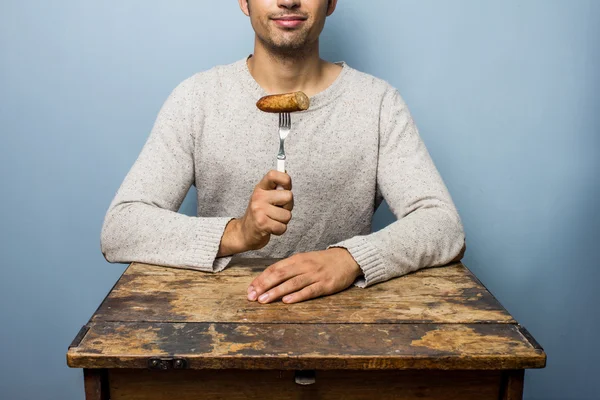 Młody człowiek jedzenie kiełbasa — Zdjęcie stockowe