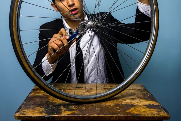 Hombre de traje tratando de arreglar un neumático de bicicleta —  Fotos de Stock