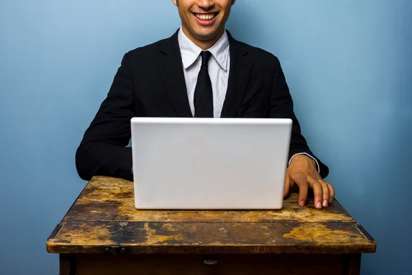 Glücklicher Geschäftsmann mit Laptop am alten Tisch — Stockfoto