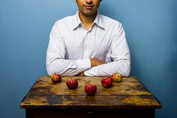 Homme avec cinq pommes disposées en flèche — Photo