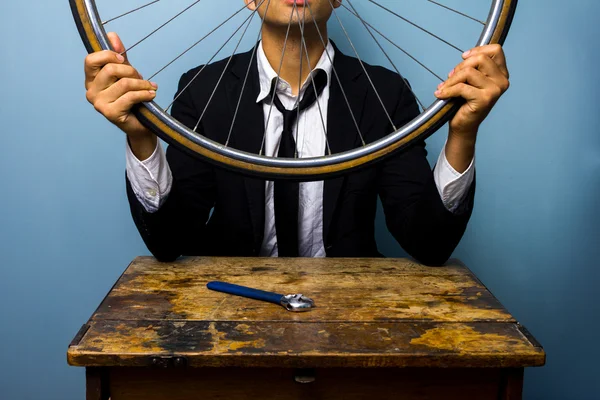 Homem de terno tentando consertar um pneu de bicicleta — Fotografia de Stock