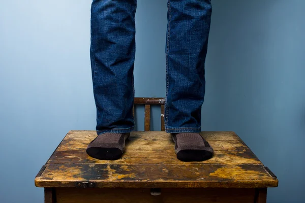 Человек в носках стоит на старом деревянном столе — стоковое фото