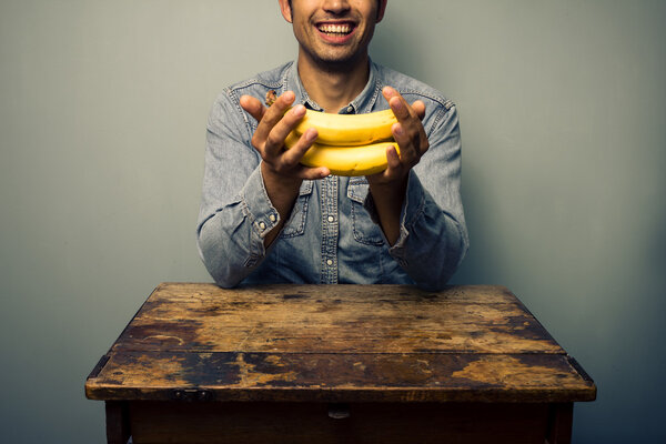 Man holding bananas at old desk
