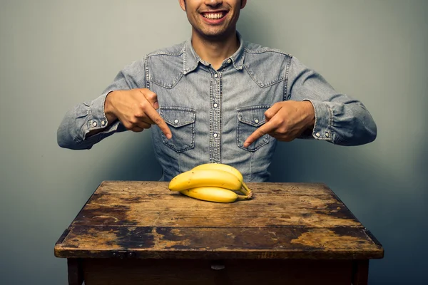 Hombre señalando plátanos en el escritorio viejo —  Fotos de Stock