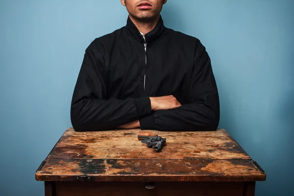 Homem à mesa com arma — Fotografia de Stock