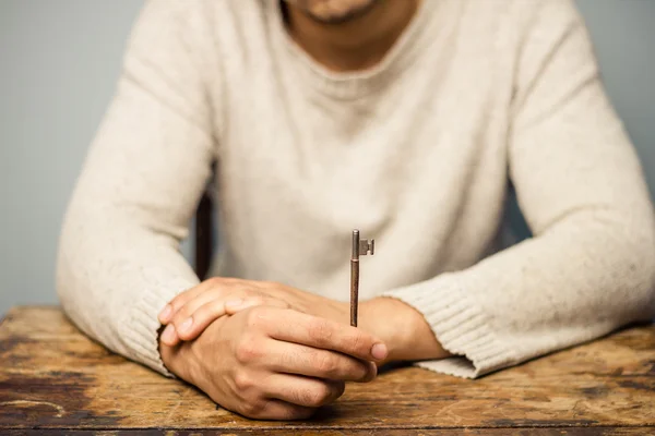 Muž u stolu drží klíč — Stock fotografie