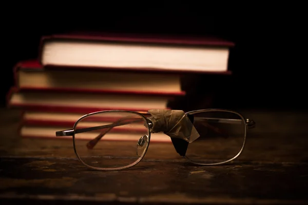Pilha de livros com um par de óculos quebrados — Fotografia de Stock