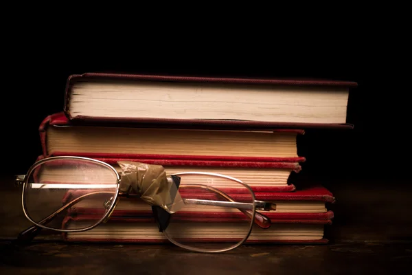 Stack of books with a pair of broken glasses — Stock Photo, Image