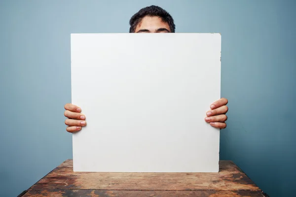 Homme au bureau caché derrière un tableau blanc — Photo