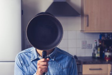 Mutfakta tavada yüzünün önünde tutan adam