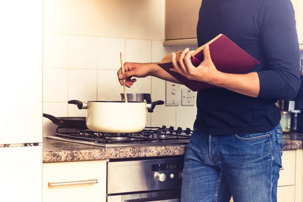 Man following a recipe and stirring his pot — Stock Photo, Image