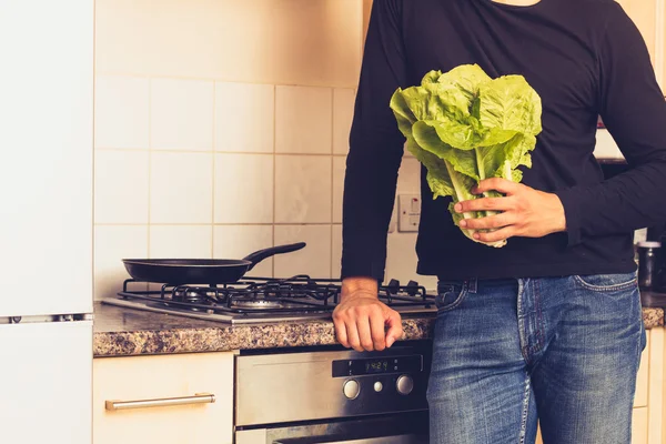 Homem com cabeça de alface na cozinha — Fotografia de Stock