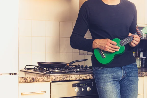 L'uomo sta giocando ukulele in cucina — Foto Stock