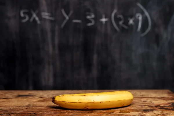 Banana por quadro negro com equação — Fotografia de Stock