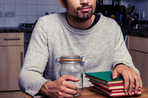 Mann mit Marmeladenglas und Bücherstapel — Stockfoto